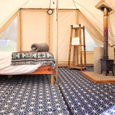 a room with a tent with a bed and a ladder at Tinker the Bell Tent at Pentref Luxury Camping in Penuwch