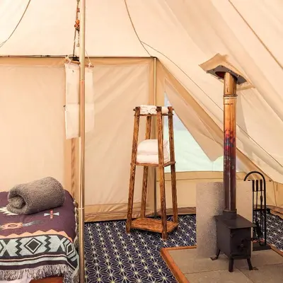 a room with a tent with a ladder and a chair at Tinker the Bell Tent at Pentref Luxury Camping in Penuwch