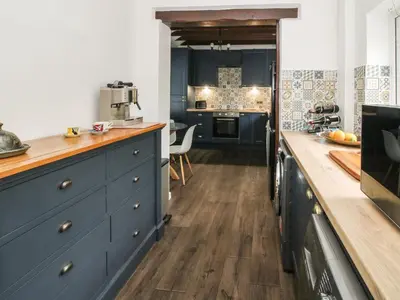 a kitchen with blue cabinets and a wooden counter top at Clematis Cottage in Shrewsbury