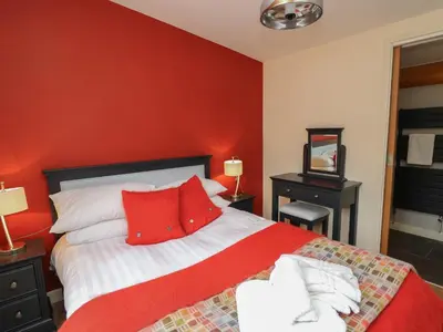 a bedroom with red walls and a bed with red pillows at Fioled in Welshpool