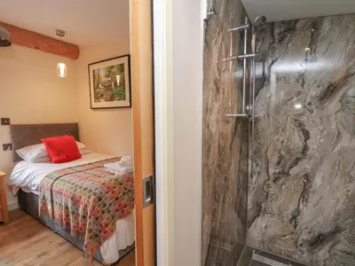 a bathroom with a shower next to a bed at Fioled in Welshpool