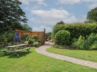 a picnic table and an umbrella in a garden at Fioled in Welshpool