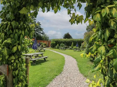 a garden with picnic tables and a gravel path at Fioled in Welshpool