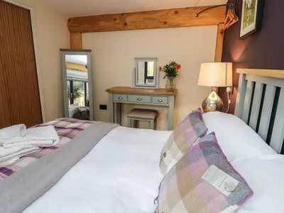 a bedroom with a white bed and a mirror at Daffodil in Welshpool