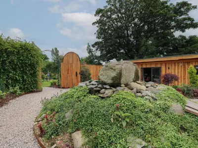 a garden with a rock and a wooden building at Daffodil in Welshpool