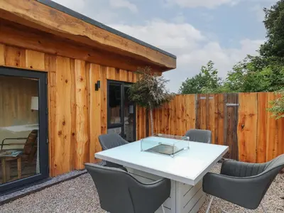 a patio with a white table and chairs in front of a fence at Daffodil in Welshpool