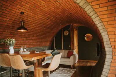 a dining room with a table and a brick wall at Otters View in Rhayader