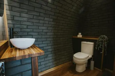 a bathroom with a white toilet and a brick wall at Otters View in Rhayader
