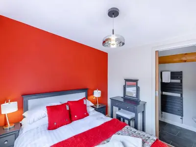 a bedroom with a red wall and a bed with red pillows at Fioled - Uk40267 in Llangadfan