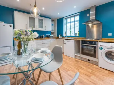 a kitchen with blue walls and a glass table and chairs at Perfectly located 2 bed townhouse in Shrewsbury - Pass the Keys in Shrewsbury