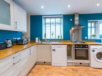 a kitchen with white cabinets and blue walls at Perfectly located 2 bed townhouse in Shrewsbury - Pass the Keys in Shrewsbury