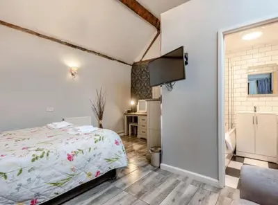 a bedroom with a bed and a flat screen tv at Curly Tail Accommodation in Bishops Castle