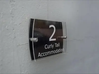 a sign on a wall that reads county fall accommodation at Curly Tail Accommodation in Bishops Castle
