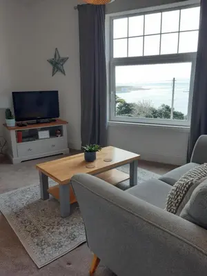 a living room with a couch and a table and a window at Seasalt Loft in Barmouth