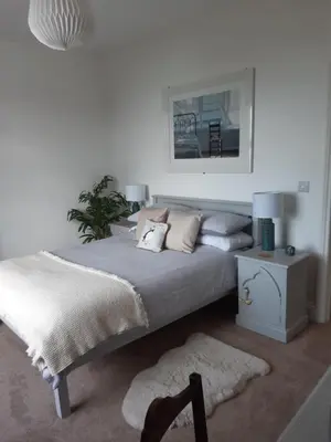 a white bedroom with a large bed and a table at Seasalt Loft in Barmouth