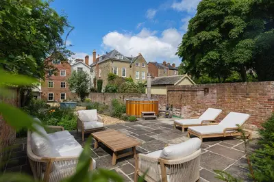 a patio with chairs and tables and a brick wall at Ludlow Townhouse in Ludlow