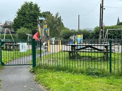 a fence in front of a park with a playground at Hill View Cottage in Bala