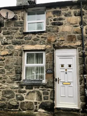 a stone building with a white door and two windows at Ty Cwtch in Dolgellau