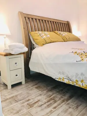 a bed with a wooden headboard next to a night stand at Ty Cwtch in Dolgellau