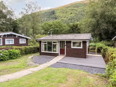a small cabin with a deck and a house at Chalet 2 in Machynlleth