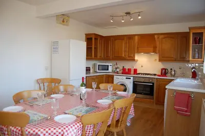 a kitchen with a table with a red and white table cloth at Angorfa family holiday home with games room in Tywyn