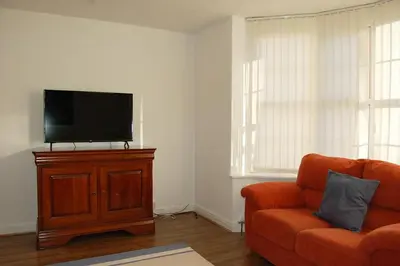 a living room with an orange couch and a flat screen tv at Angorfa family holiday home with games room in Tywyn