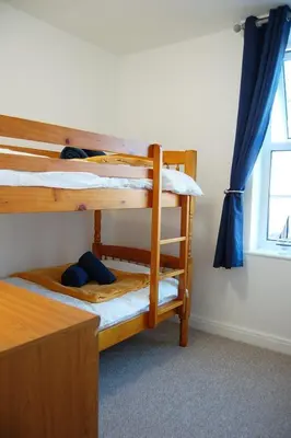 two bunk beds in a room with a window at Angorfa family holiday home with games room in Tywyn