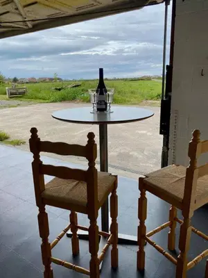 a table with a bottle of wine and two chairs at Angorfa family holiday home with games room in Tywyn