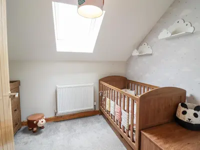 a baby room with a crib and a skylight at Llys Tirion in Bala