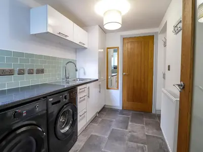 a kitchen with a washer and dryer and a door at Llys Tirion in Bala