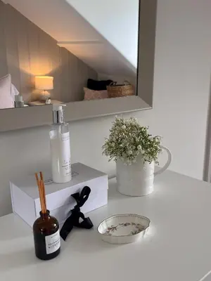 a white counter with a bottle and a bowl of flowers at Efail Fach in New Quay