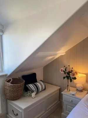 a room with a bed and a table with a vase of flowers at Efail Fach in New Quay