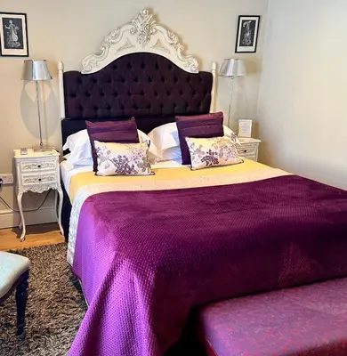a bedroom with a large purple bed with two pillows at The New White Lion in Llandovery