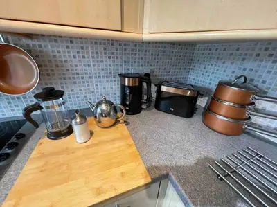 a kitchen counter with a wooden cutting board and appliances at Yew Tree Cottage, 3 bedroom, 4 Church Row Defynnog in Devynock