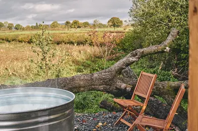 a wooden chair sitting next to a barrel and a tree at Big Sky Hideaway in Leominster