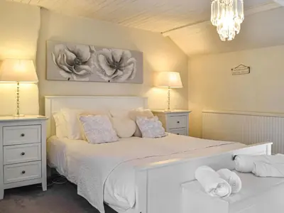 a bedroom with a white bed with two night stands at Penlan Cottage in Cwrt-newydd