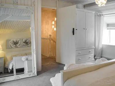 a white bedroom with a mirror and a bed at Penlan Cottage in Cwrt-newydd