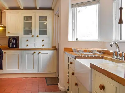 a kitchen with white cabinets and a sink and a window at Penlan Cottage in Cwrt-newydd