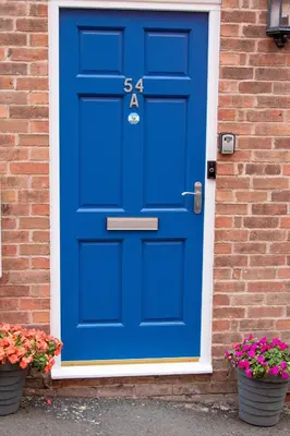a blue door on a brick house with two pots of flowers at Relaxing Town Centre House - Perfect for Exploring in Shrewsbury
