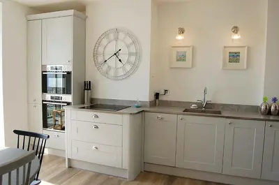 a kitchen with a sink and a clock on the wall at Driftwood Designer Apartment in Tywyn