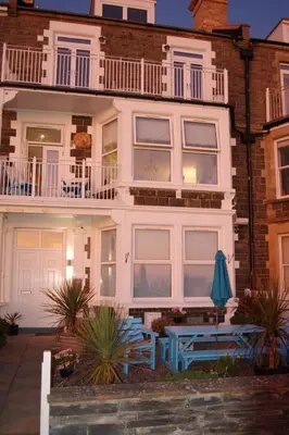a house with two blue benches in front of it at Driftwood Designer Apartment in Tywyn