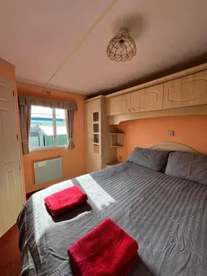 a bedroom with a bed with two red towels on it at Holiday Home by the sea in Aberystwyth