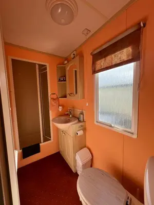a bathroom with a sink and a toilet and a window at Holiday Home by the sea in Aberystwyth