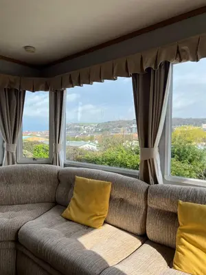 a couch with yellow pillows in a room with windows at Holiday Home by the sea in Aberystwyth