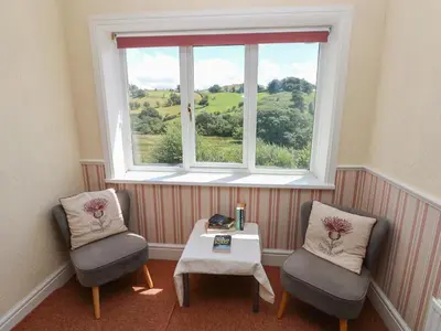 a room with two chairs and a table and a window at Hillside Lodge in Llandrindod Wells