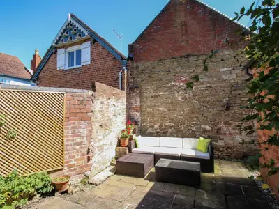 a patio with a white couch and a brick wall at Dinham Court in Ludlow