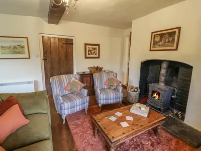 a living room with a couch and a wood stove at Grove Cottage in Leominster