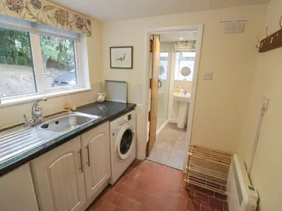 a bathroom with a sink and a washing machine at Grove Cottage in Leominster
