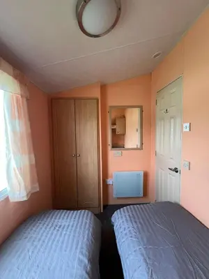 a bedroom with orange walls and a bed and a window at Light and Airy 2 Bedroom Mobile Home in Aberystwyth