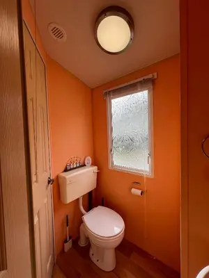 an orange bathroom with a toilet and a window at Light and Airy 2 Bedroom Mobile Home in Aberystwyth